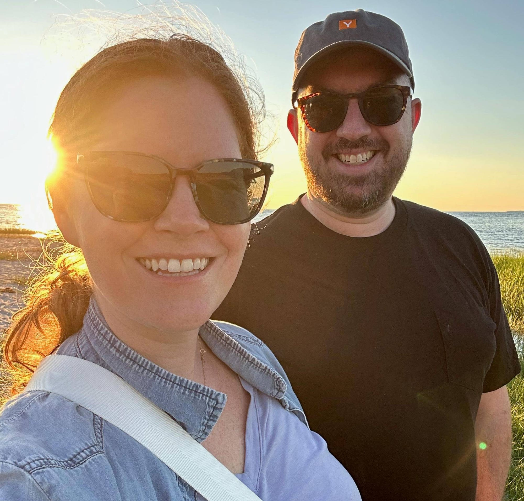 A couple (Mike and I) looking at the camera with a sunset in the background.