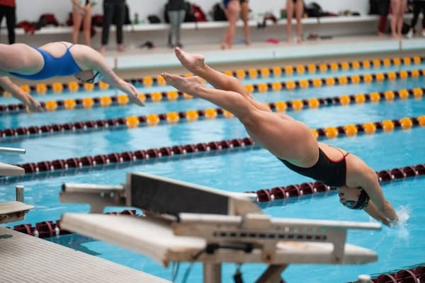 Swimmers diving into a pool.